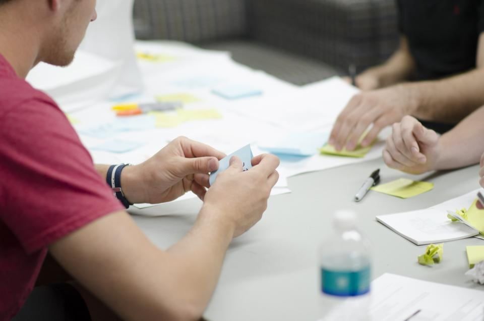 Two people planning work together around a table covered in sticky notes