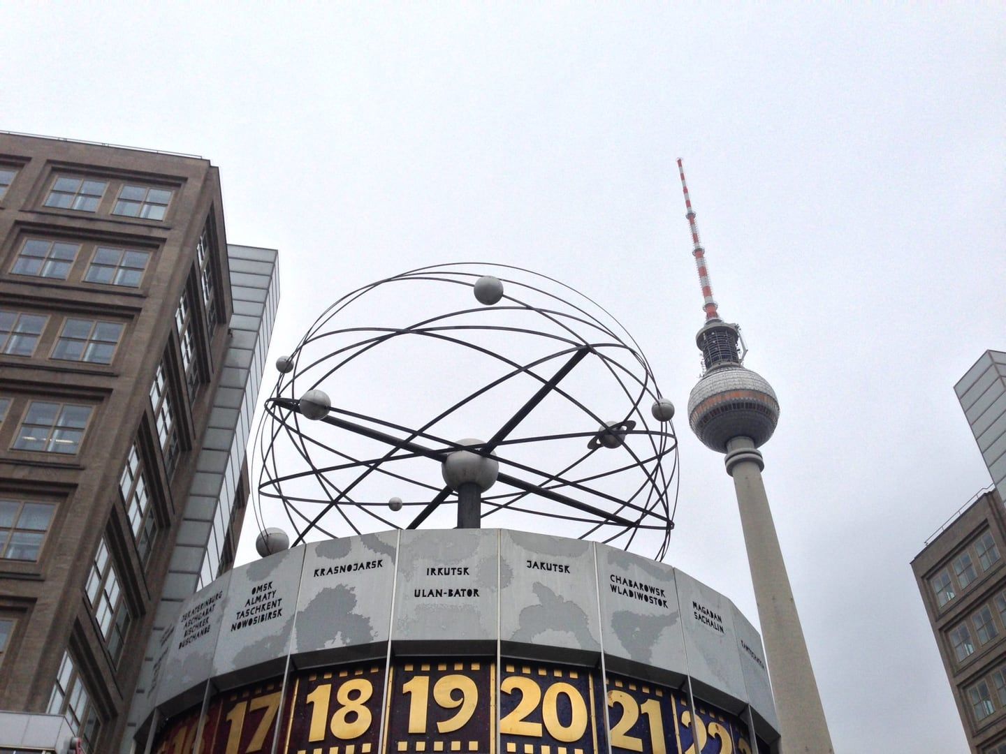 The World Time Clock at Alexanderplatz in Berlin, showing times around the world, against a grey sky