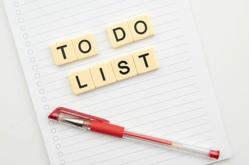 Letter tiles spelling TO DO LIST on a lined notepad next to a red pen